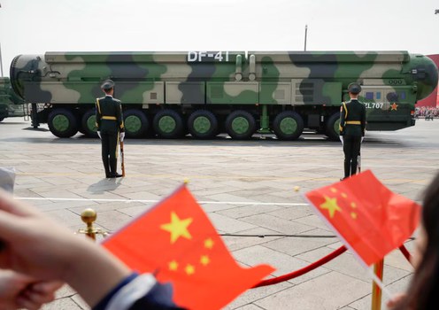 Spectators wave Chinese flags at military vehicles carrying DF-41 ballistic missiles during a parade to commemorate the 70th anniversary of the founding of Communist China in Beijing, Oct. 1, 2019.