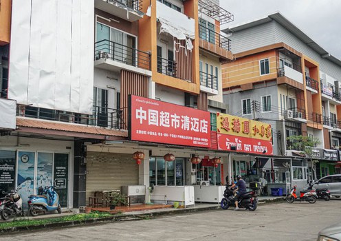 A motorcyclist parks in front of business advertising in Chinese in Thailand’s Hang Dong district in Chiang Mai province, Nov. 10, 2024.